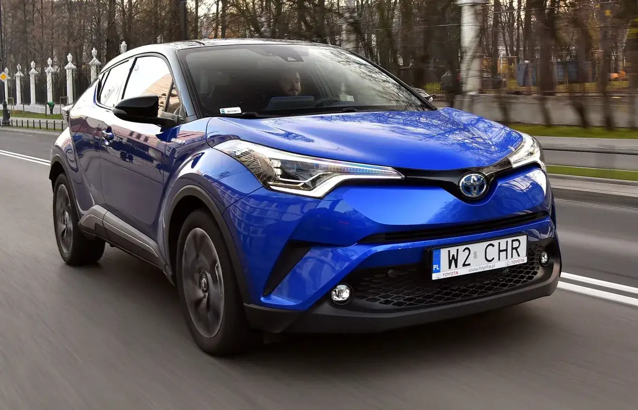Niebieska Toyota C-HR w ruchu ulicznym. Kierowca za kierownicą. Warto sprawdzić, czy nie występują typowe toyota chr usterki.