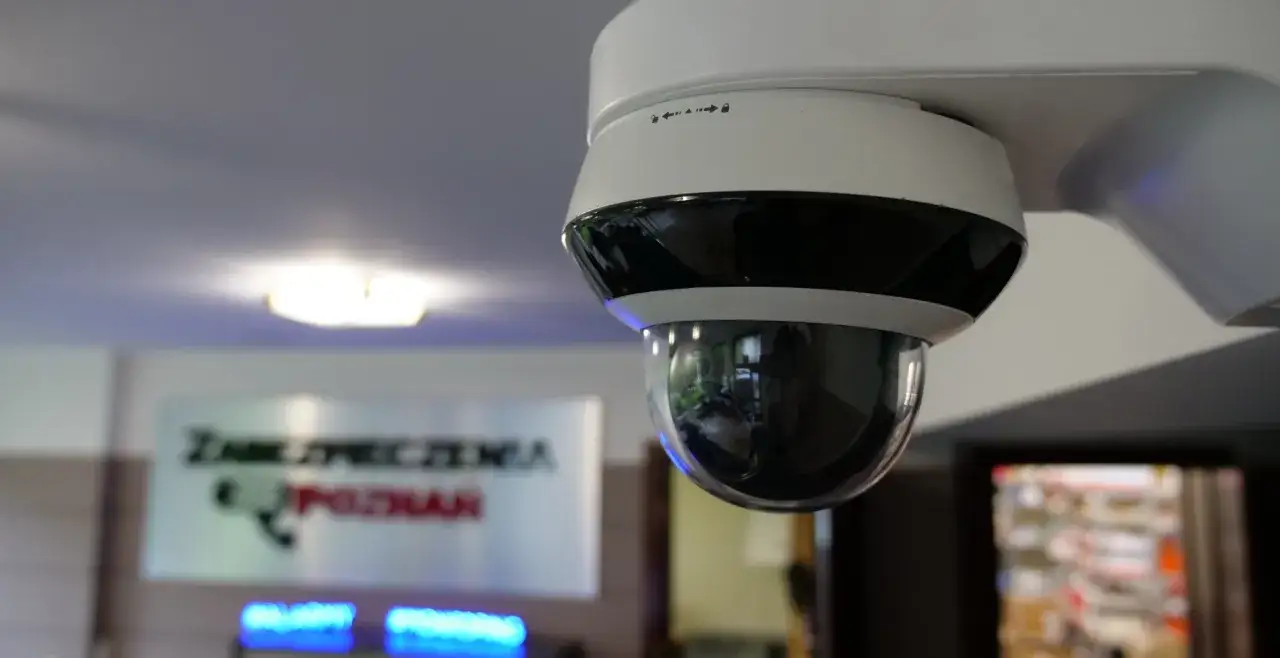 Kamera monitoringu w biurze, zapewniająca kontrolę pracownika. W tle tablica 