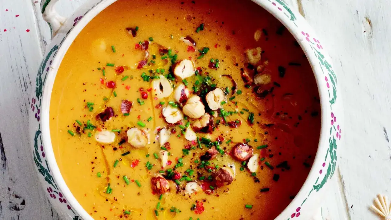 Soupe butternut onctueuse, garnie de noisettes concass&eacute;es, de ciboulette cisel&eacute;e et de baies roses. Un d&eacute;lice r&eacute;confortant.