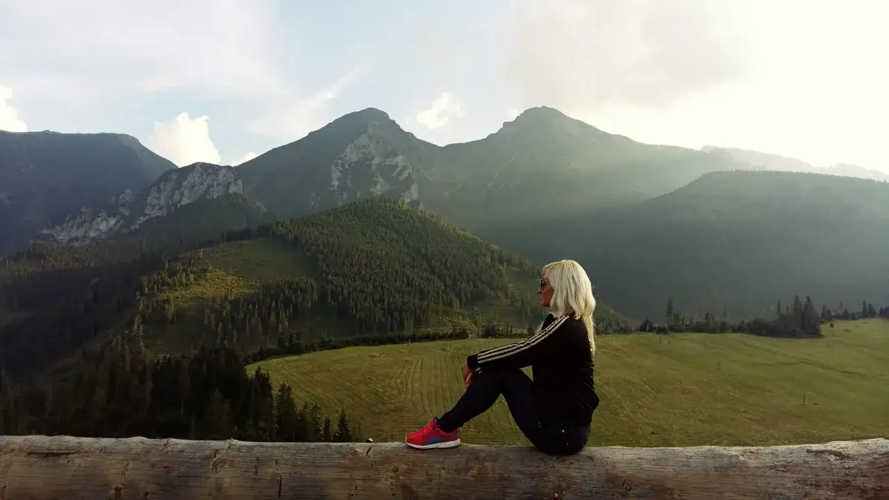 Kobieta podziwia górskie **zdziar atrakcje**. Widok na szczyty i lasy.