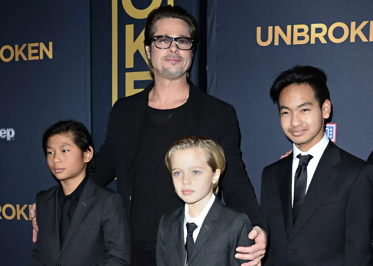 Brad Pitt z dziećmi na premierze. Aktor w okularach stoi z tyłu, a przed nim jego dzieci w eleganckich strojach.