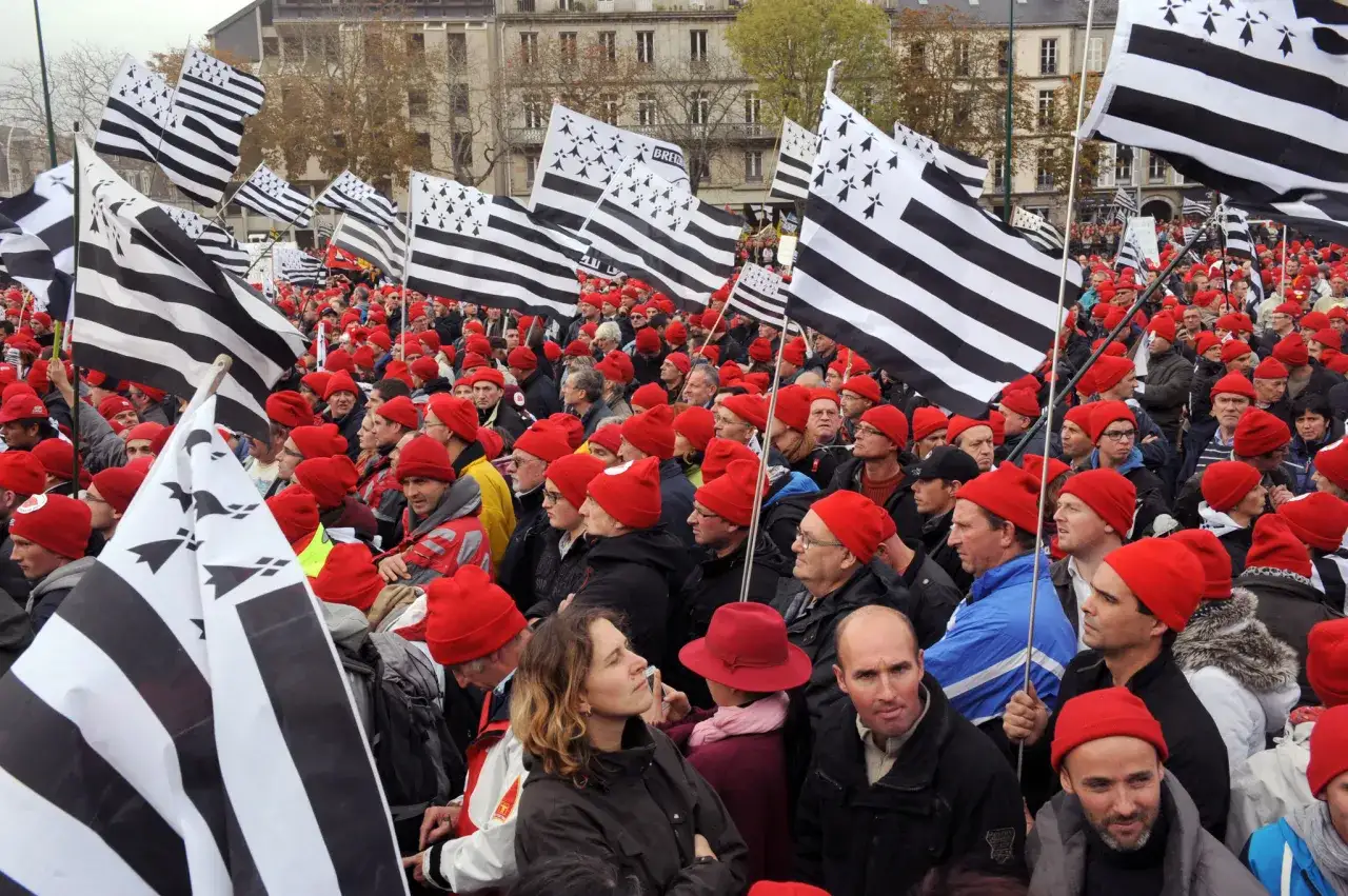 Foule portant le bonnet rouge breton, brandissant des drapeaux bretons.