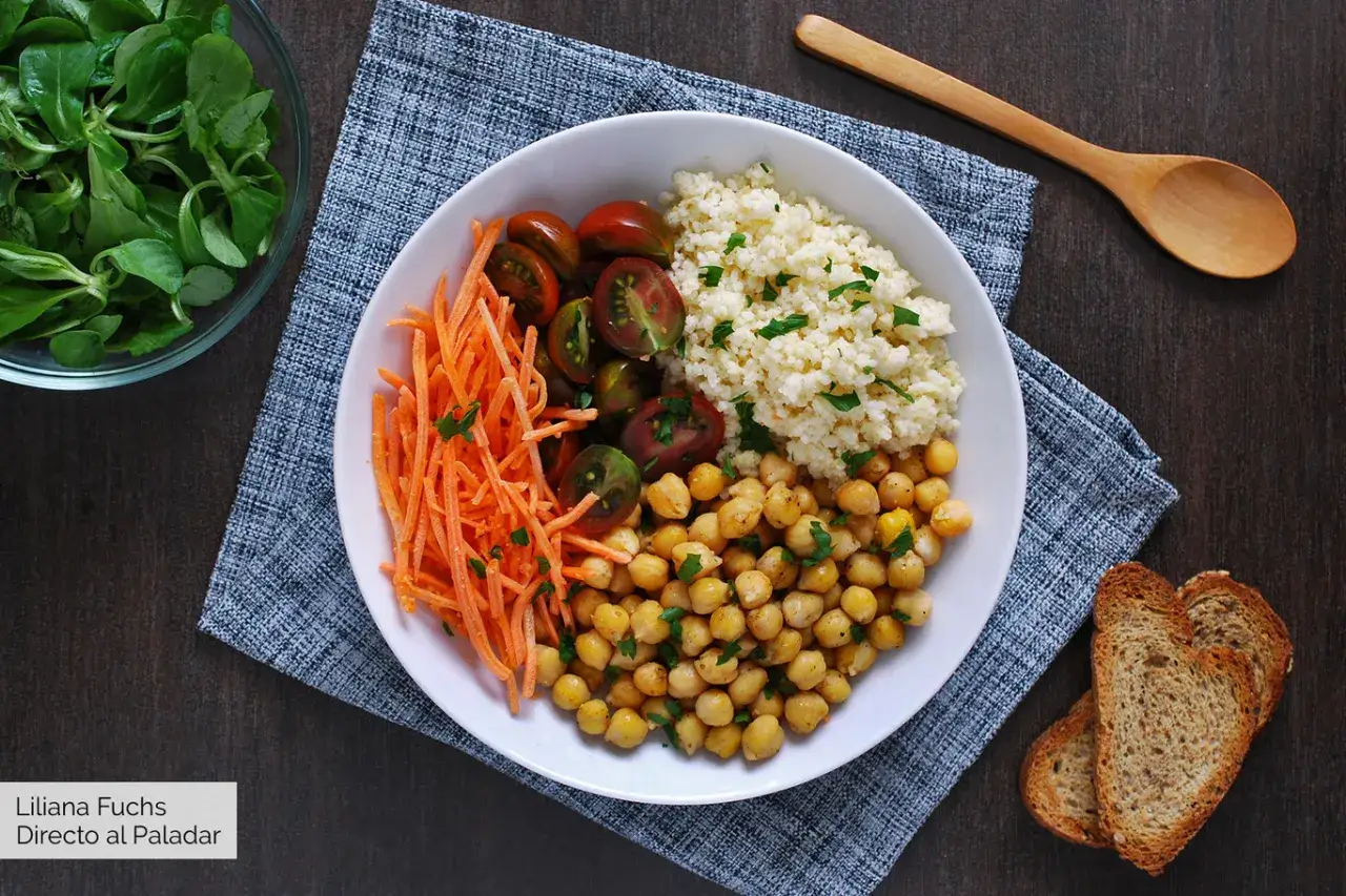 Un plato del buen comer con garbanzos, cusc&uacute;s, zanahoria rallada y tomates cherry. Acompa&ntilde;ado de pan tostado y una ensalada verde.