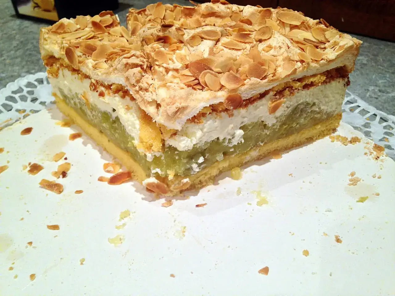 Ein saftiger Stachelbeer Baiser Kuchen mit Mandelsplittern. Die grüne Fruchtschicht und die luftige Baisermasse sind ein Genuss.