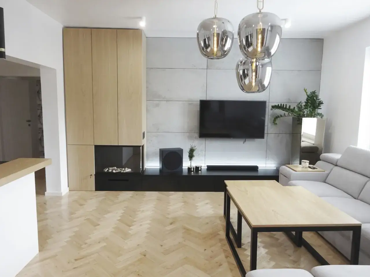 Nowoczesna zabudowa ściany w salonie: drewniane fronty, beton architektoniczny, kominek i TV. Inspiracje dla Twojego wnętrza.