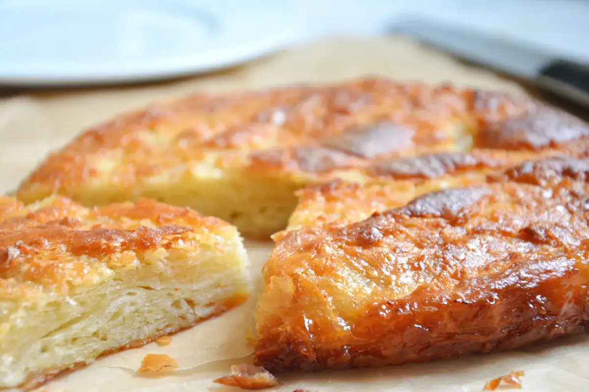 Kouign amann, ein knuspriger, karamellisierter Kuchen mit geschichteten Teigschichten, liegt auf Backpapier.
