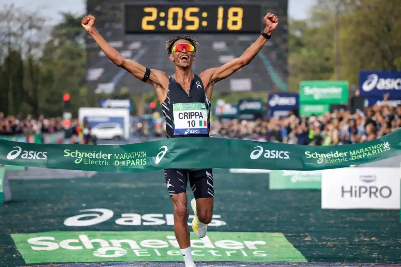 Crippa taglia il traguardo della maratona, braccia alzate in segno di vittoria. Il cronometro segna 2:05:18.