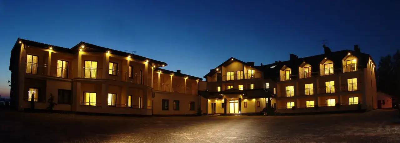 Hotel spa Rusałka nocą, z oświetlonymi oknami i balkonami, tworzy przytulną atmosferę.