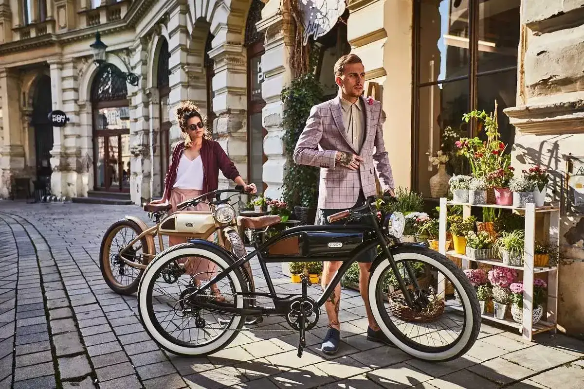 Para zrozumieć, jak działa rower elektryczny, spójrz na te stylowe pojazdy. Mężczyzna i kobieta pozują obok nich na brukowanej uliczce.