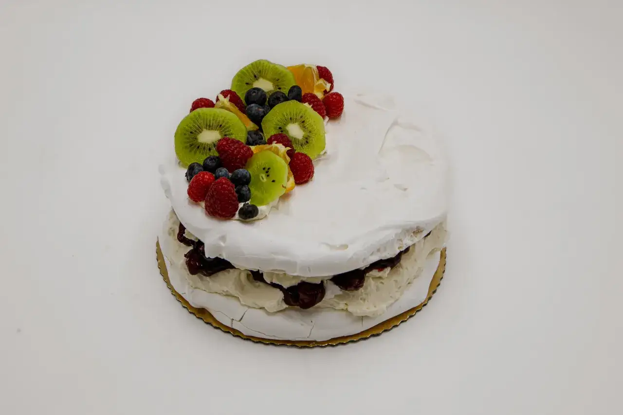 Pyszny tort bezowy z owocami, idealny na deser. Zastanawiasz się, ile kosztuje tort bezowy w cukierni? Ten wygląda na wart swojej ceny!