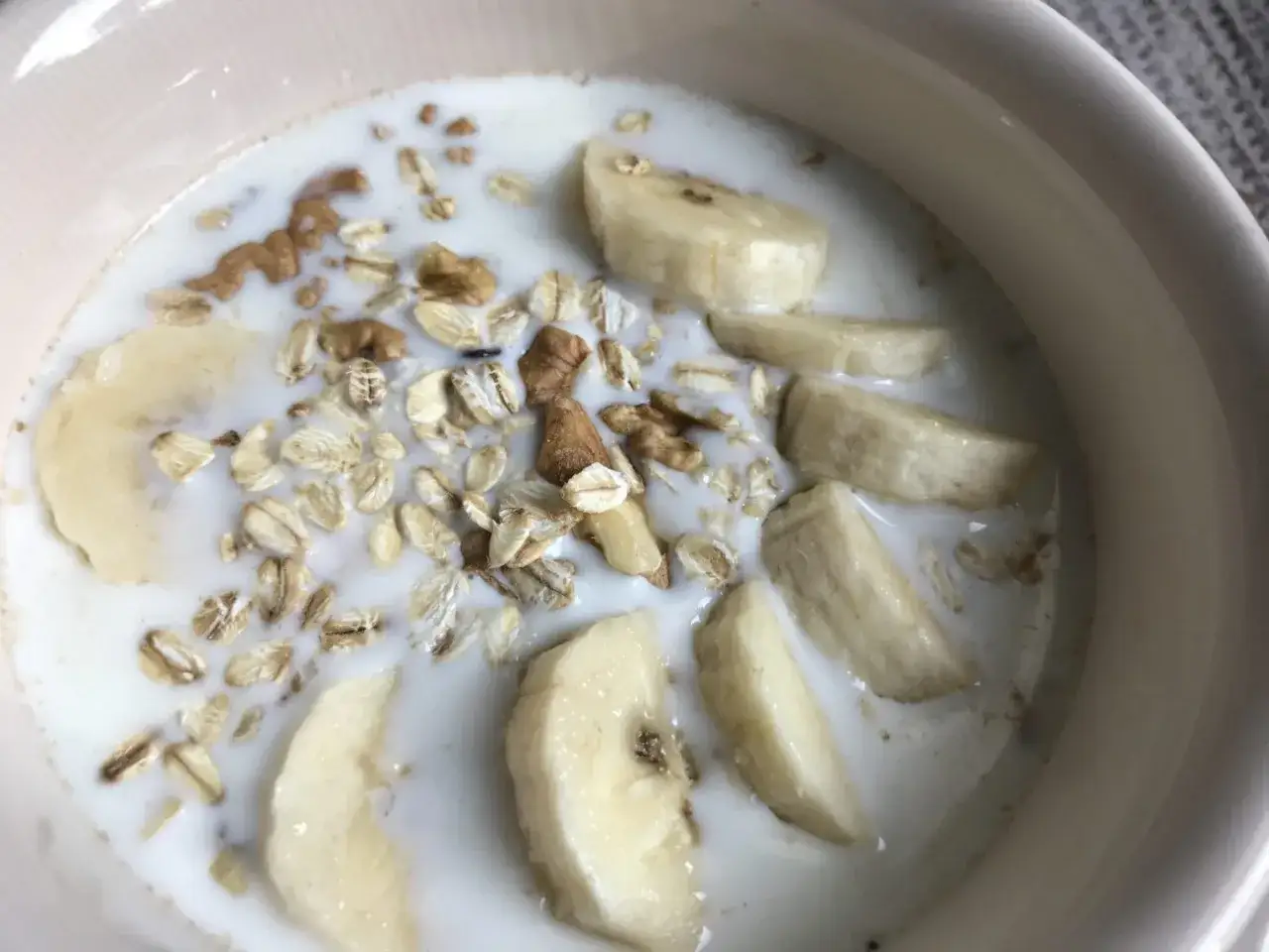 Una ciotola con fiocchi d'avena, fette di banana e noci in latte. Un modo sano e gustoso per iniziare la giornata, scopri come mangiare i fiocchi d'avena!