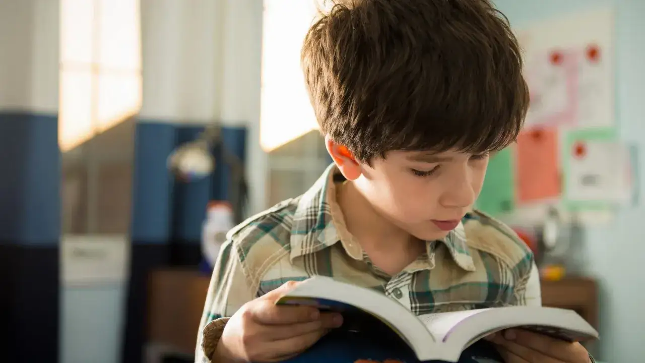 Niño concentrado en ejercicios de comprensión lectora, con un libro abierto.