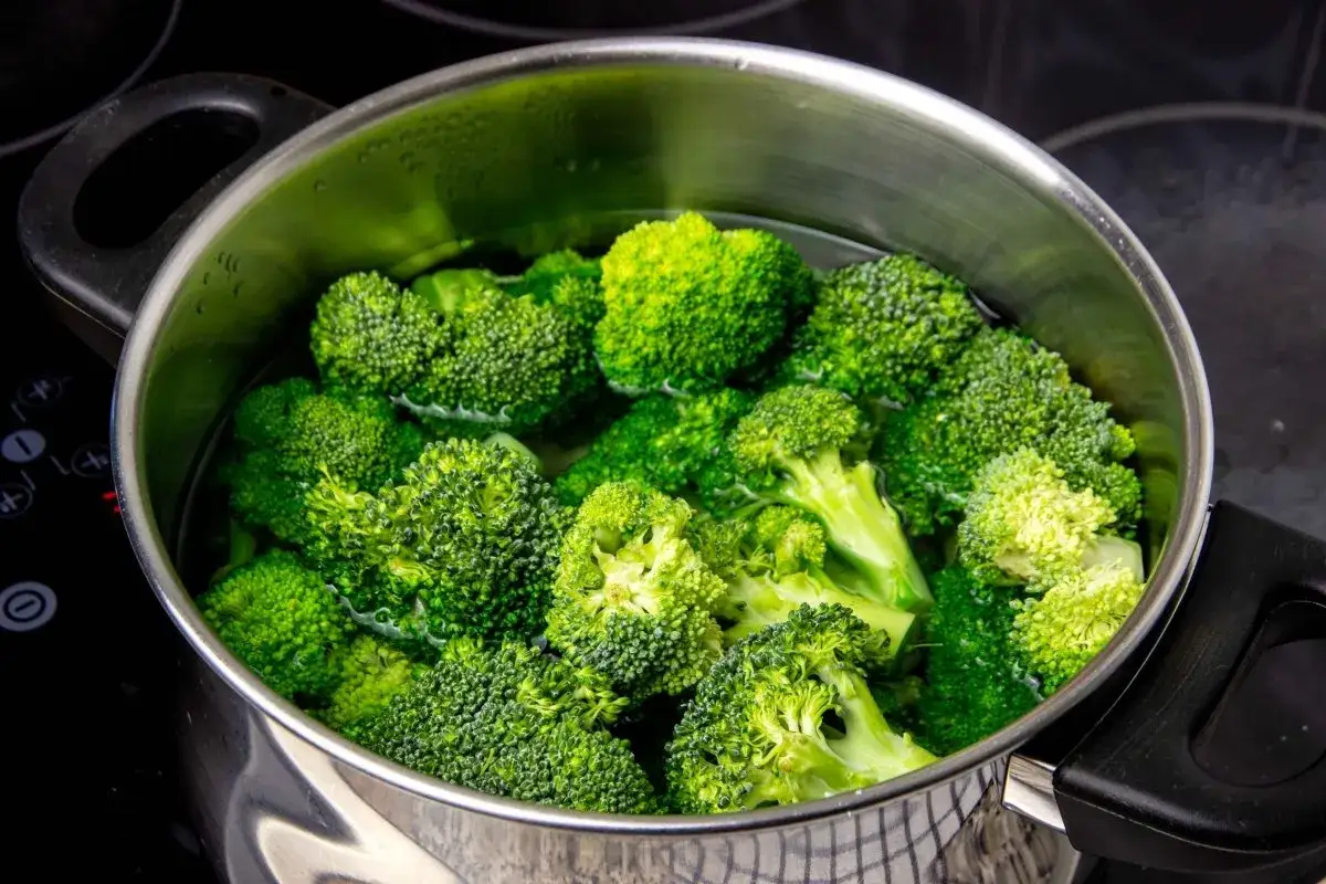 Brotes de br&oacute;coli frescos y verdes sumergidos en agua hirviendo en una olla de metal. Preparando para cocer br&oacute;coli.