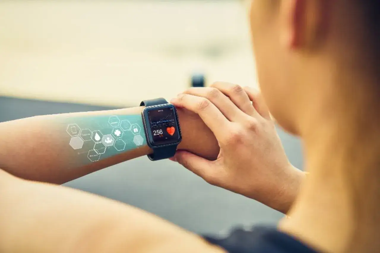Osoba sprawdza na smartwatchu swoje tętno i kalorie. Widoczne są ikony zdrowia, co to jest smartwatch i jego funkcje.
