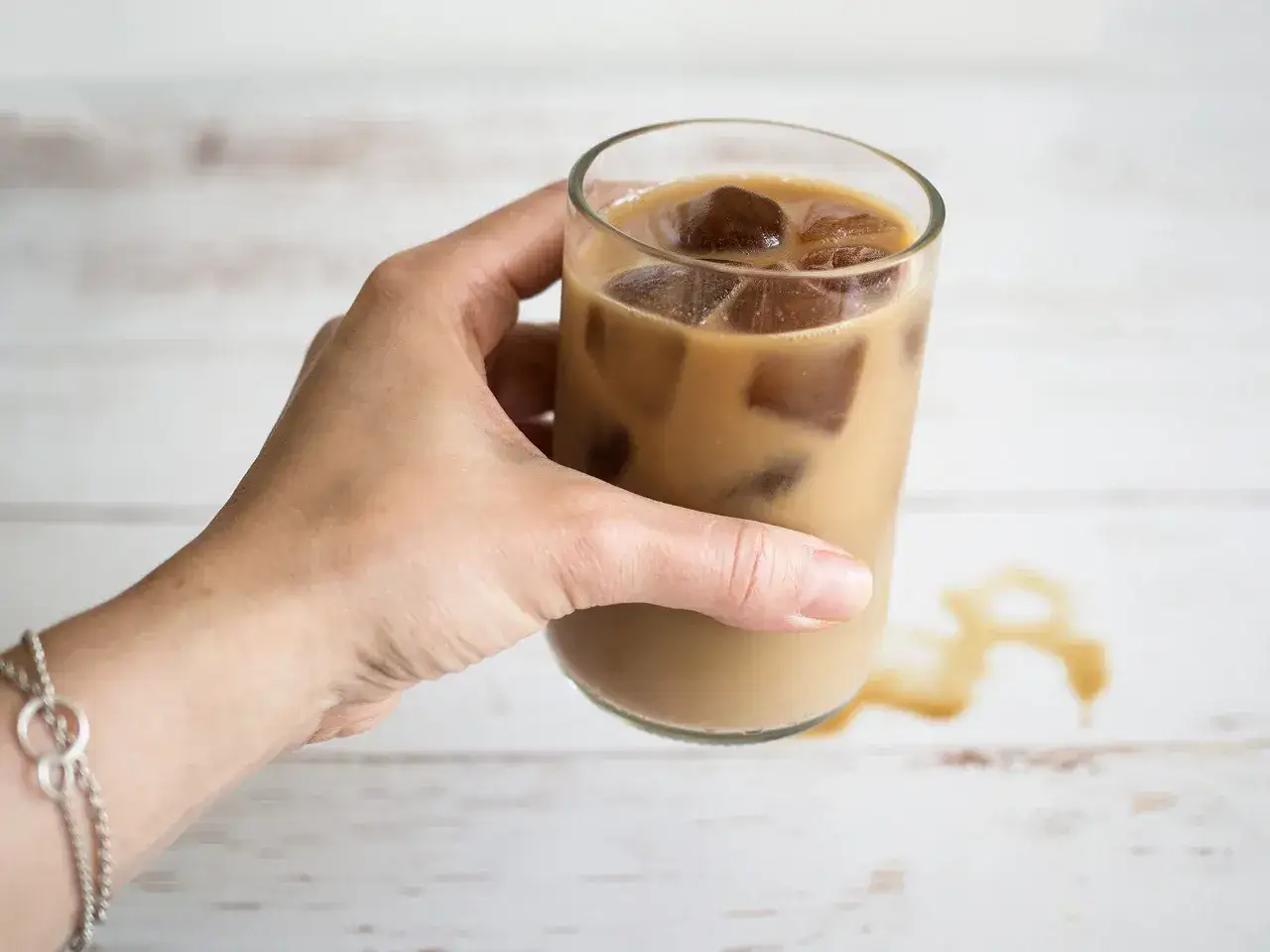 En hand håller ett glas iskaffe, perfekt för ett enkelt iskaffe recept.