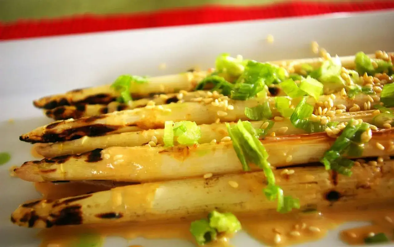 Gegrillter Spargel mit Sesam und Frühlingszwiebeln, beträufelt mit einer cremigen Sauce. Ein köstliches Gericht, das Lust auf mehr macht.