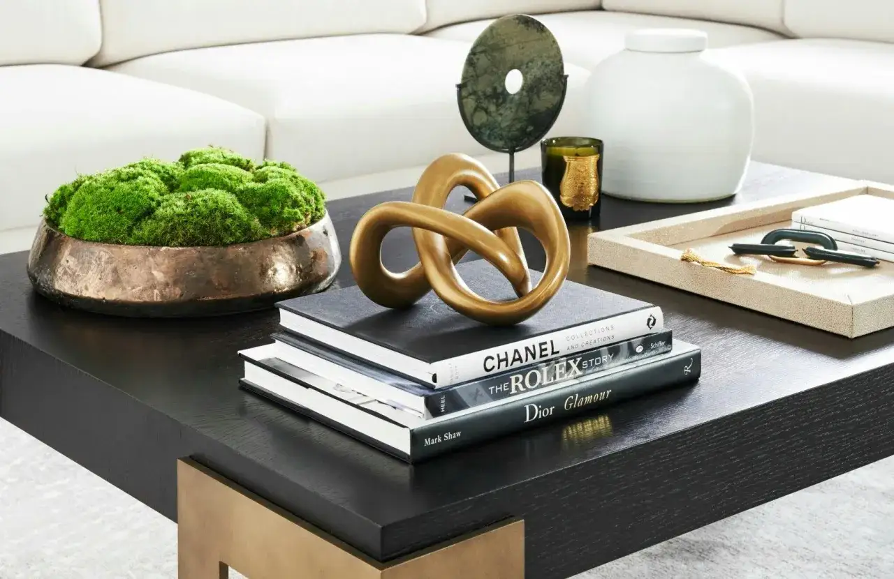 Soffbord med konstverk, b&ouml;cker om Chanel, Rolex och Dior, samt en mossk&aring;l. En perfekt inspiration f&ouml;r att styla soffbord.