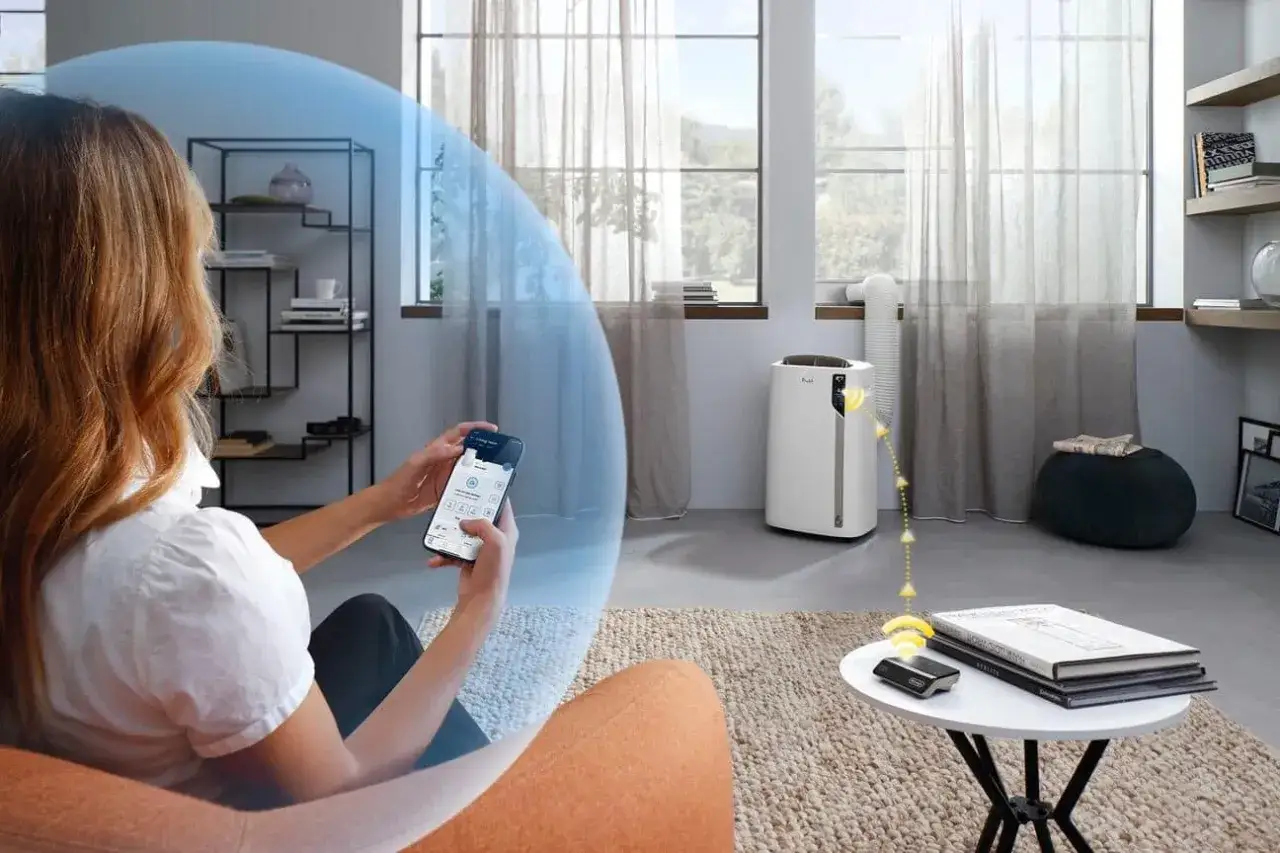 Une femme contrôle à distance son climatiseur Delonghi PAC EL112 CST WiFi via son smartphone, pour un confort optimal.