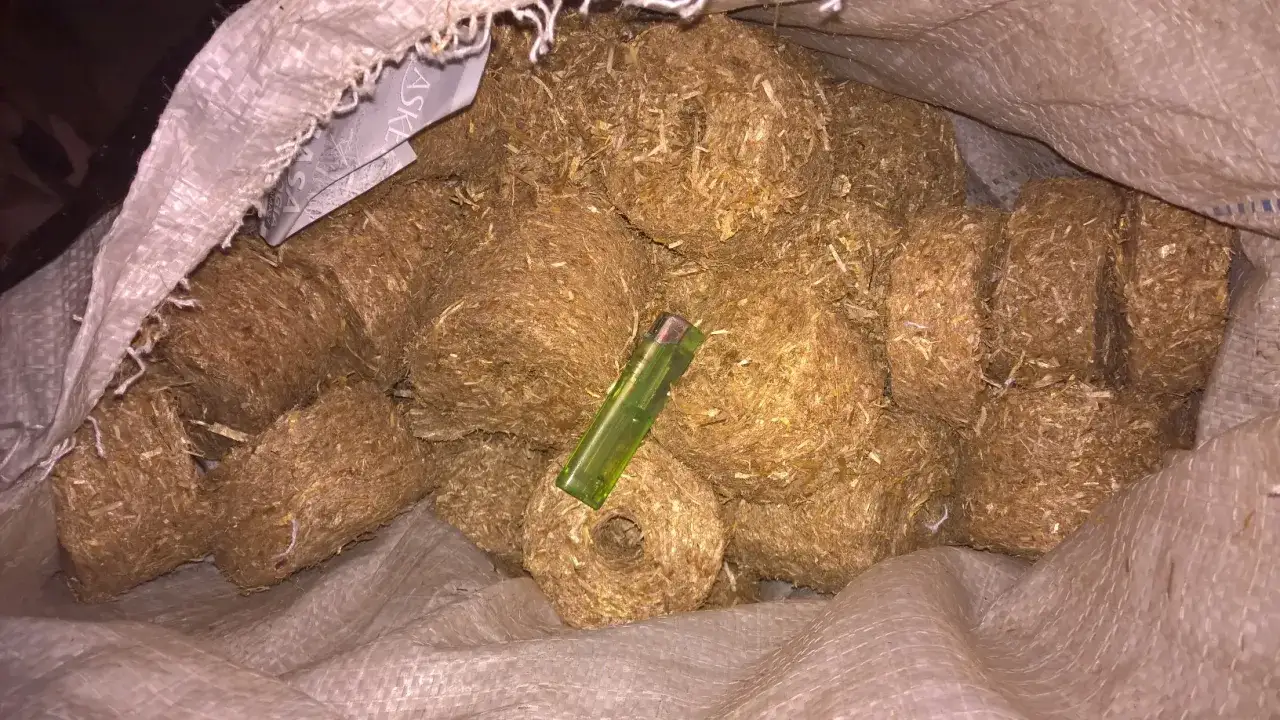 Worek pełen brykietów ze słomy, gotowych do użycia jako ekologiczne paliwo. Widać zieloną zapalniczkę, która daje skalę.