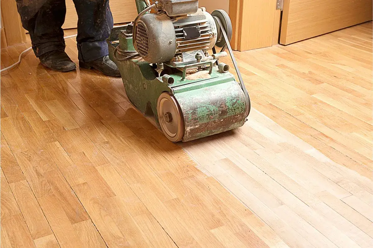 Arbeiter schleift mit einer Maschine einen Holzboden, um das Parkett zu versiegeln.