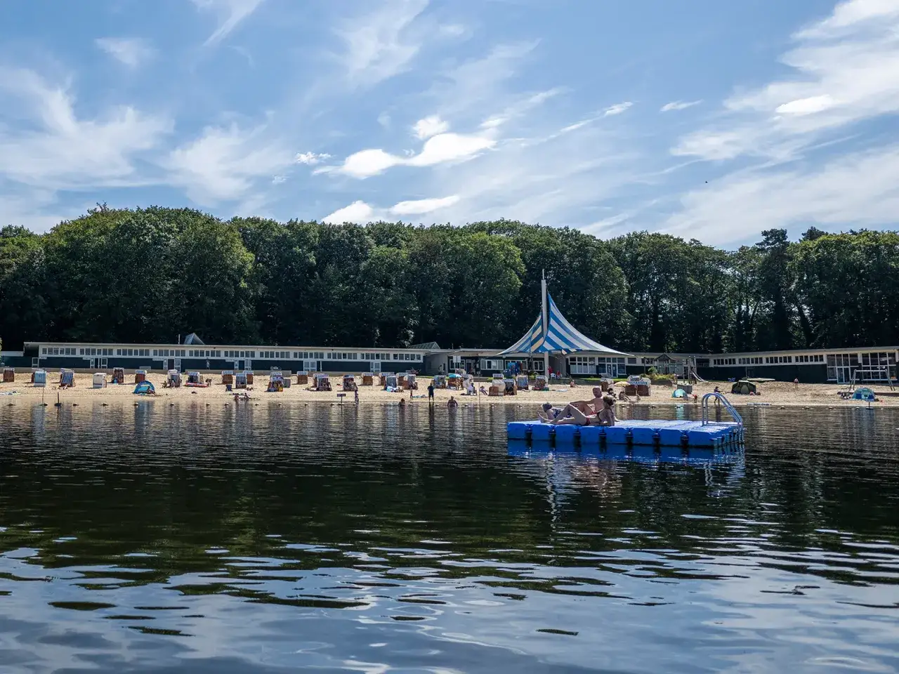 Entspannter Tag am haltern am see strand. Menschen genießen die Sonne auf Strandkörben und einer schwimmenden Plattform.