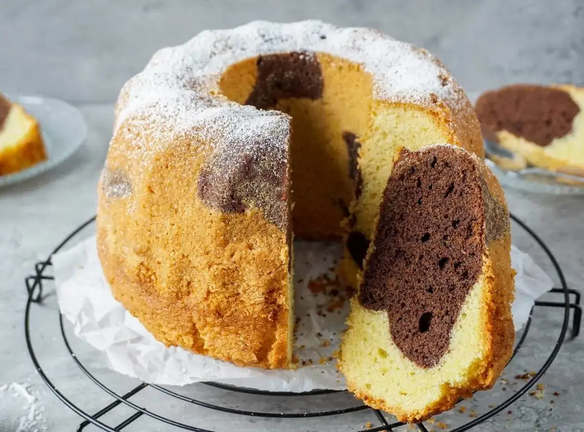 Saftiger Marmorkuchen, der weltbeste, mit Puderzucker bestäubt. Ein Stück wurde abgetrennt, um die köstliche Marmorierung zu zeigen.