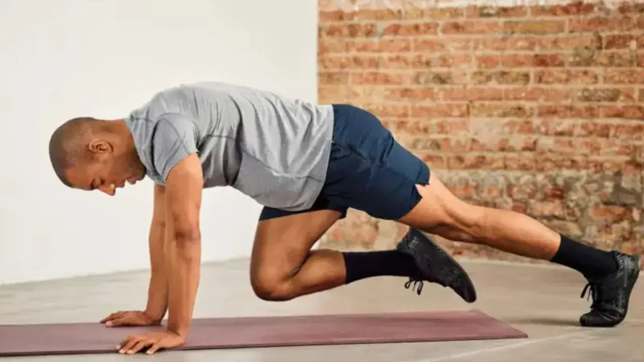 Mężczyzna wykonuje ćwiczenie mountain climbers na macie. Intensywny trening całego ciała.