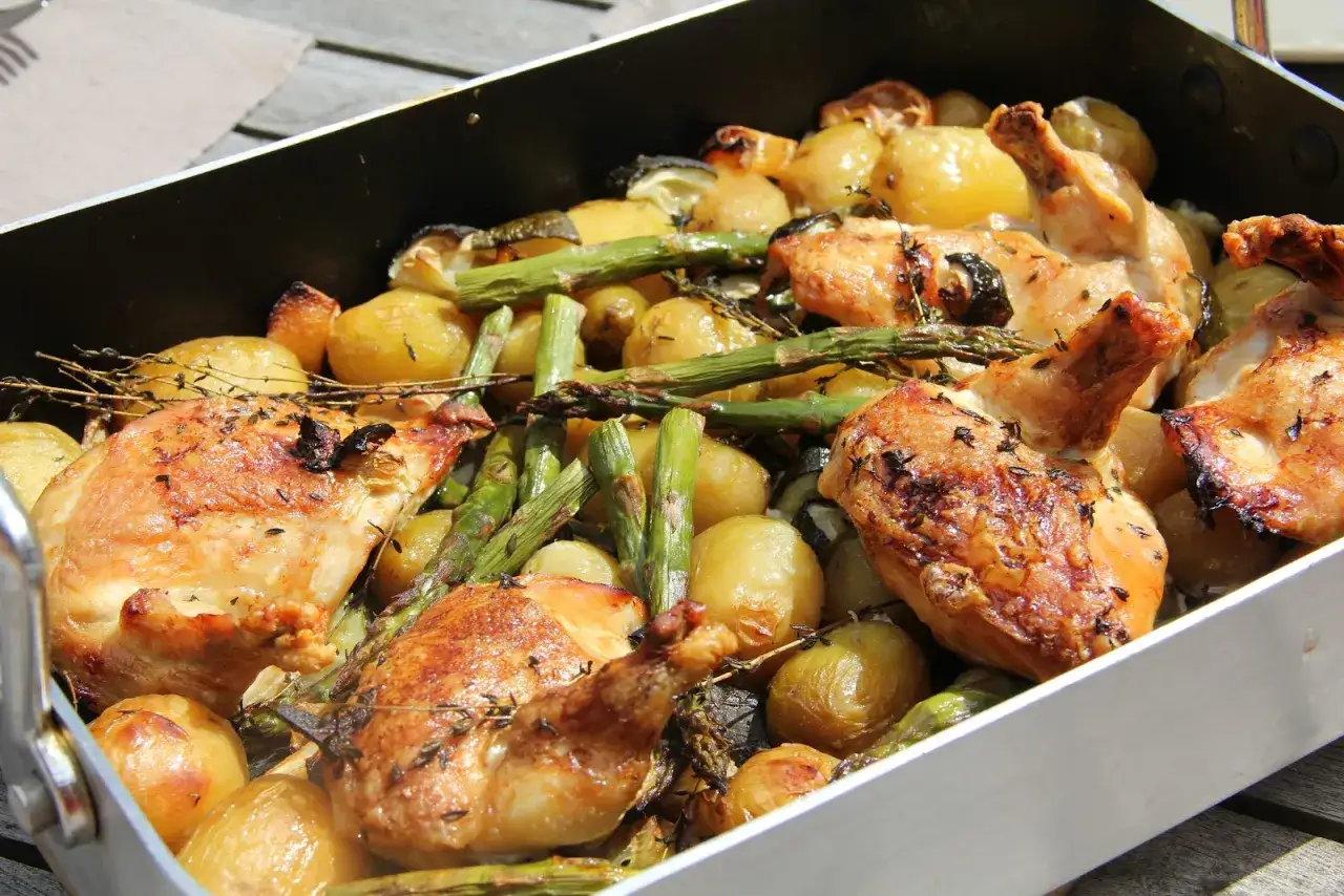Un plat de filet de poulet r&ocirc;ti avec des pommes de terre et des asperges, garni d'herbes fra&icirc;ches.