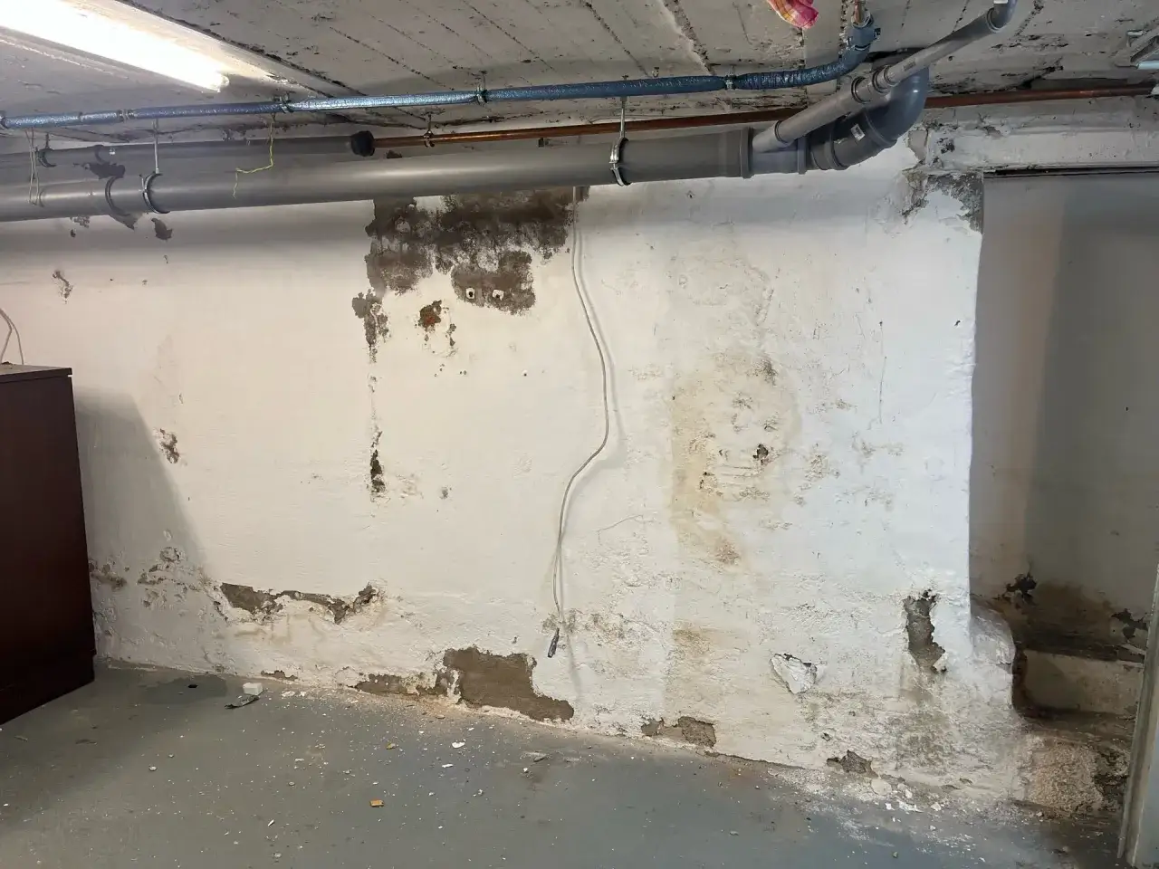 Feuchtigkeit im Keller selbst beseitigen: Abbl&auml;tternder Putz und dunkle Flecken an der Wand deuten auf Probleme hin. Rohre verlaufen an der Decke.