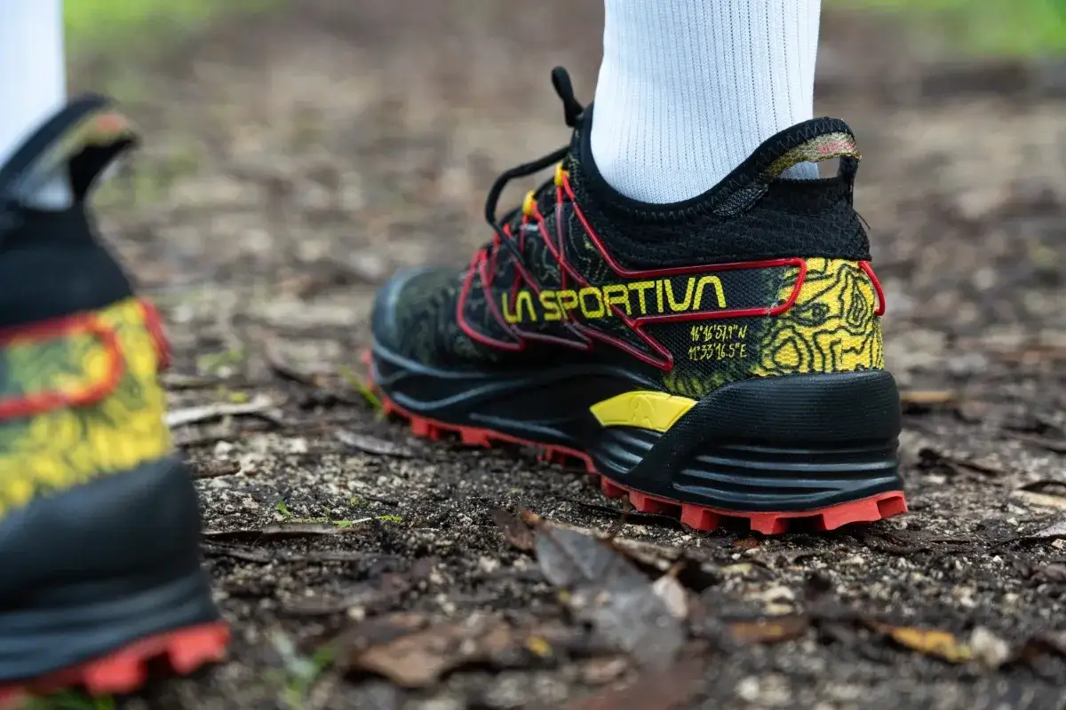 Scarpe trail running La Sportiva con suola rossa e dettagli gialli su terreno sterrato. Il loro significato &egrave; avventura e performance.