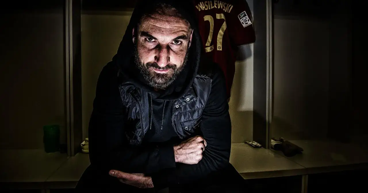 Wasilewski w szatni, zdeterminowany mimo kontuzji. Na ścianie wisi jego koszulka z numerem 27.