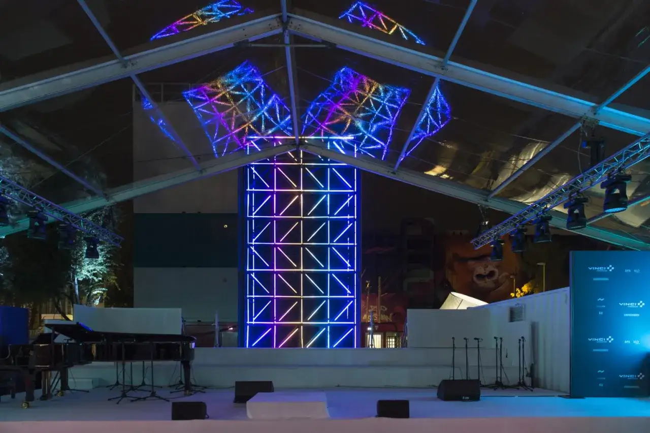 Sc&egrave;ne illumin&eacute;e de n&eacute;ons color&eacute;s, pr&ecirc;te &agrave; accueillir un festival de musique. Un piano &agrave; queue et des micros attendent les artistes.