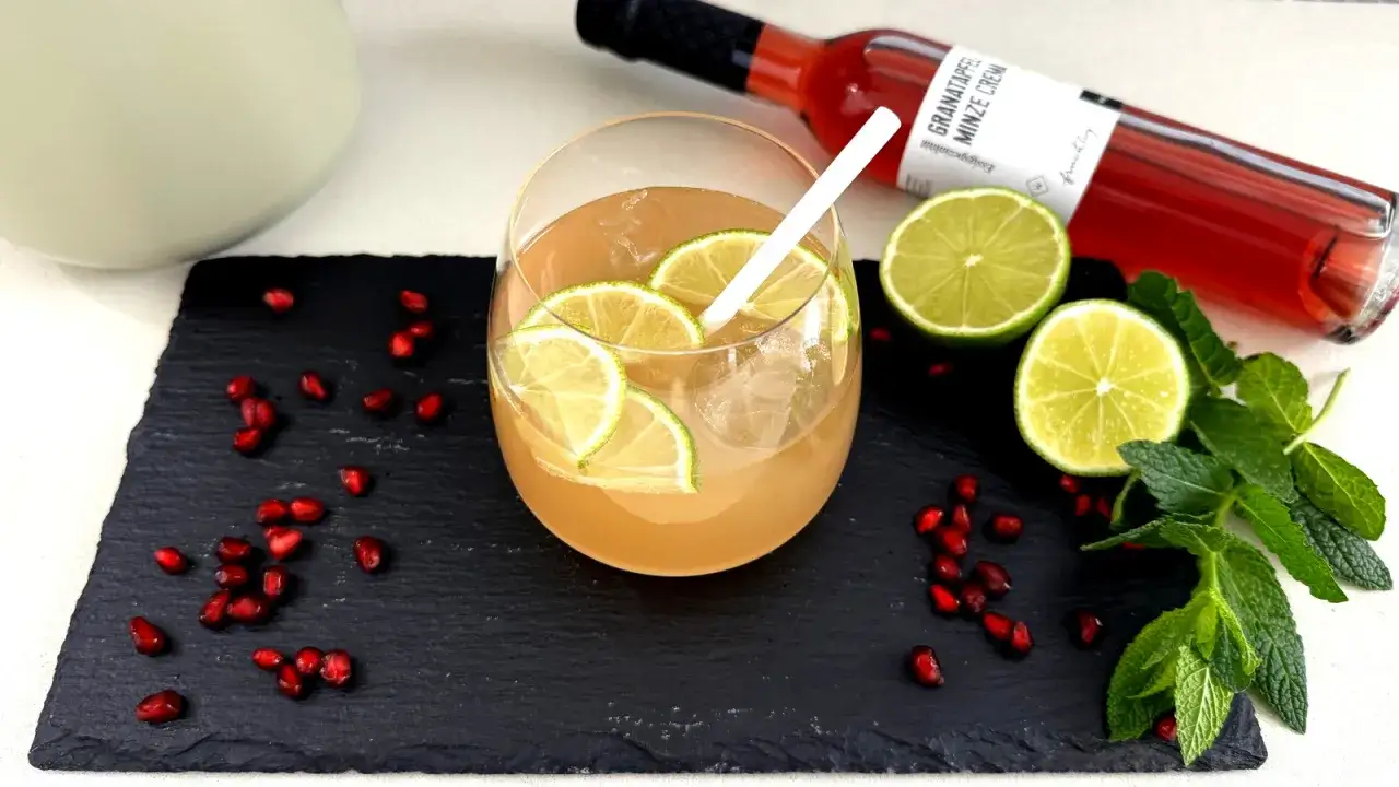 Erfrischende alkoholfreie Bowle mit Limettenscheiben, Granatapfelkernen und Minze. Perfekt für heiße Tage.