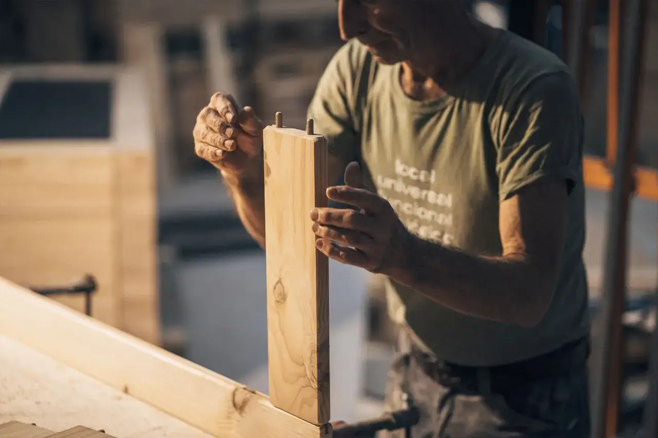 Carpintero ensambla piezas de madera, un ejemplo de cómo reparar madera dañada con precisión y cuidado.