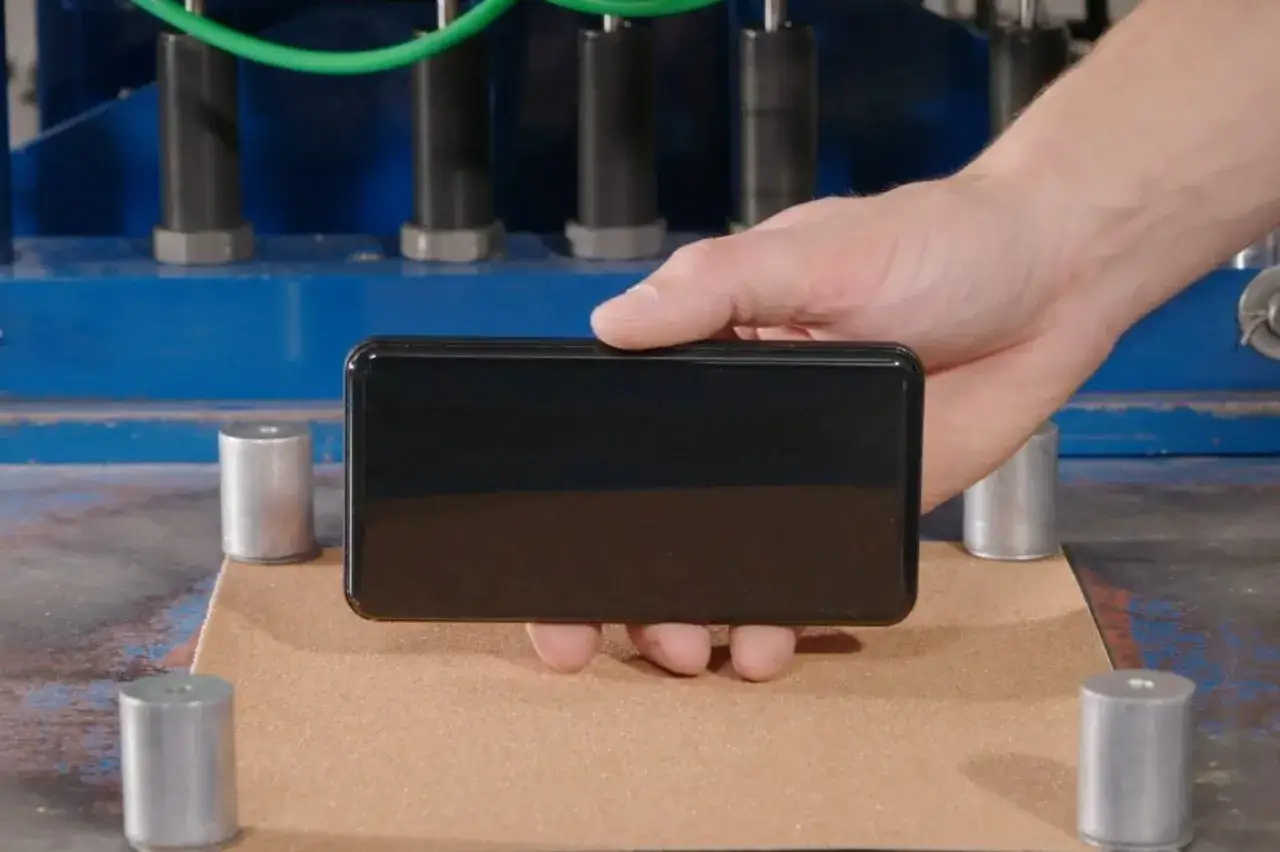 Main d'une personne tenant un smartphone avec écran en Gorilla Glass Victus 2, prêt pour un test de chute.