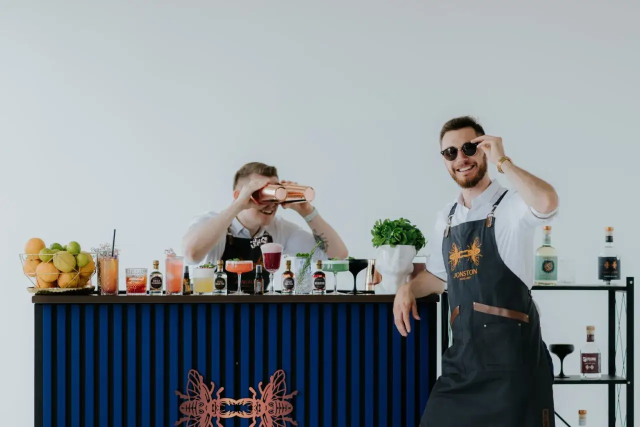 Dwóch barmanów przy barze z drinkami i owocami. Idealny pomysł, jak zaplanować bar tematyczny z wódkami świata na event.