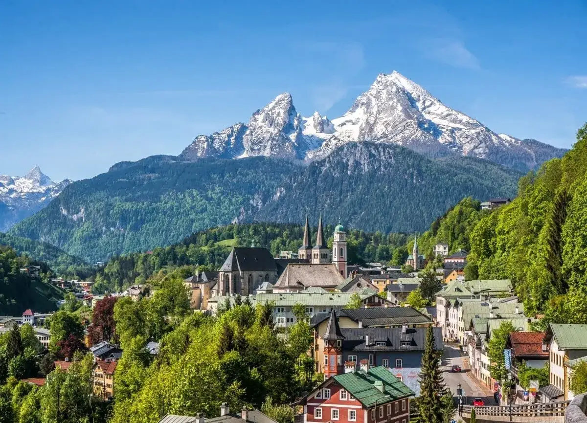 A picturesque town nestled in the Bavarian countryside, with snow-capped mountains looming majestically in the background.