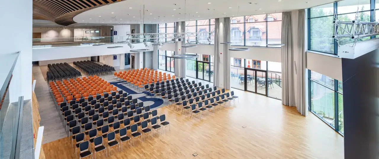 Nowoczesna sala konferencyjna z rzędami krzeseł, idealna na konferencje na Mazurach. Duże okna wpuszczają mnóstwo światła.