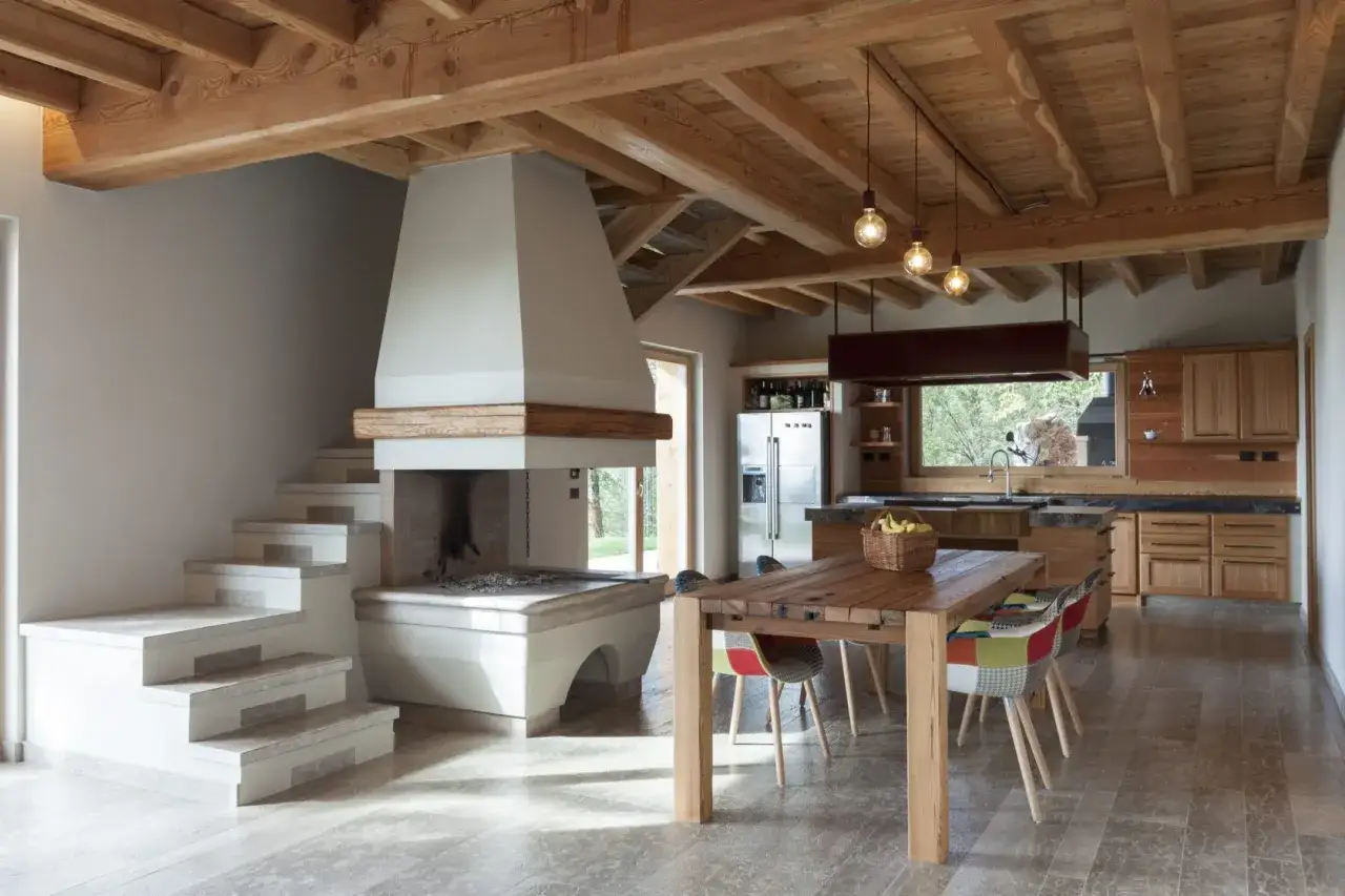 Interno moderno con camino imponente, cucina in legno e tavolo da pranzo. Il **casa prefabbricata costo** è accessibile per questo stile.