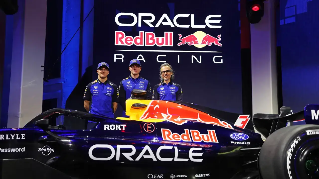 El equipo Red Bull F1 presenta su nuevo monoplaza. Tres miembros del equipo posan frente al coche y el logo de Oracle Red Bull Racing.