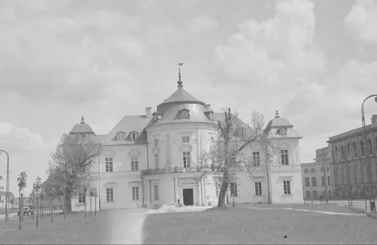 Odbudowa Pałacu Saskiego w Warszawie po wojnie. Biały, barokowy budynek z kopułą i wieżyczkami, otoczony zielenią.