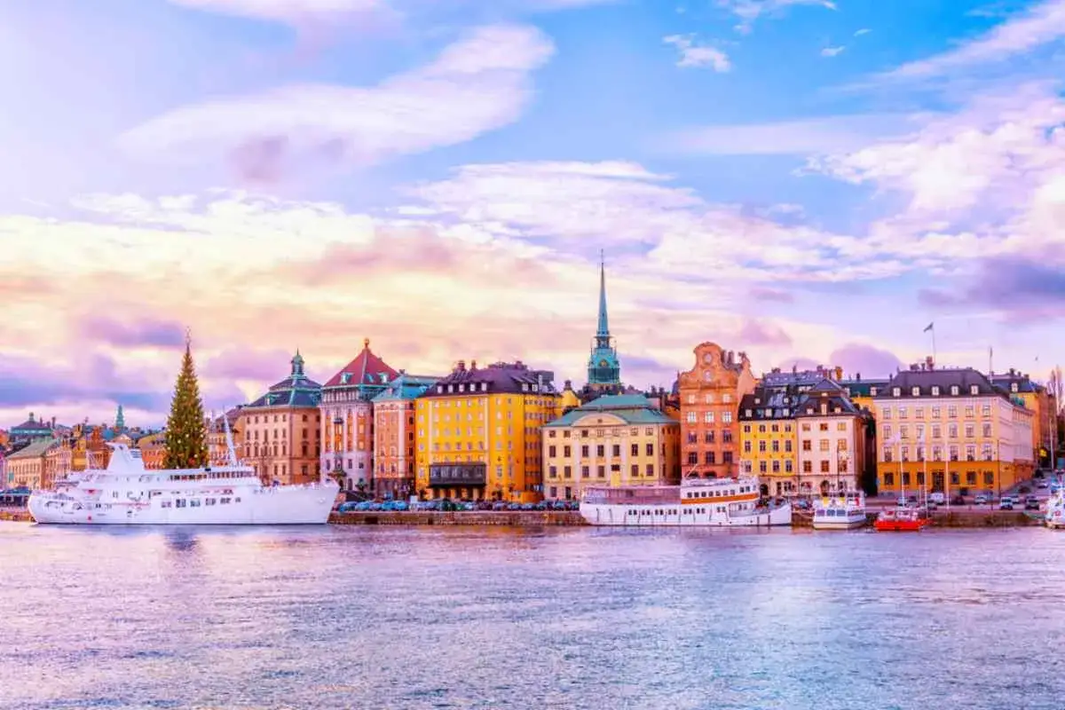 Färgglada hus och fartyg vid vattnet i Gamla Stan, Stockholm, med en julgran som sticker upp. En perfekt plats för vandring.