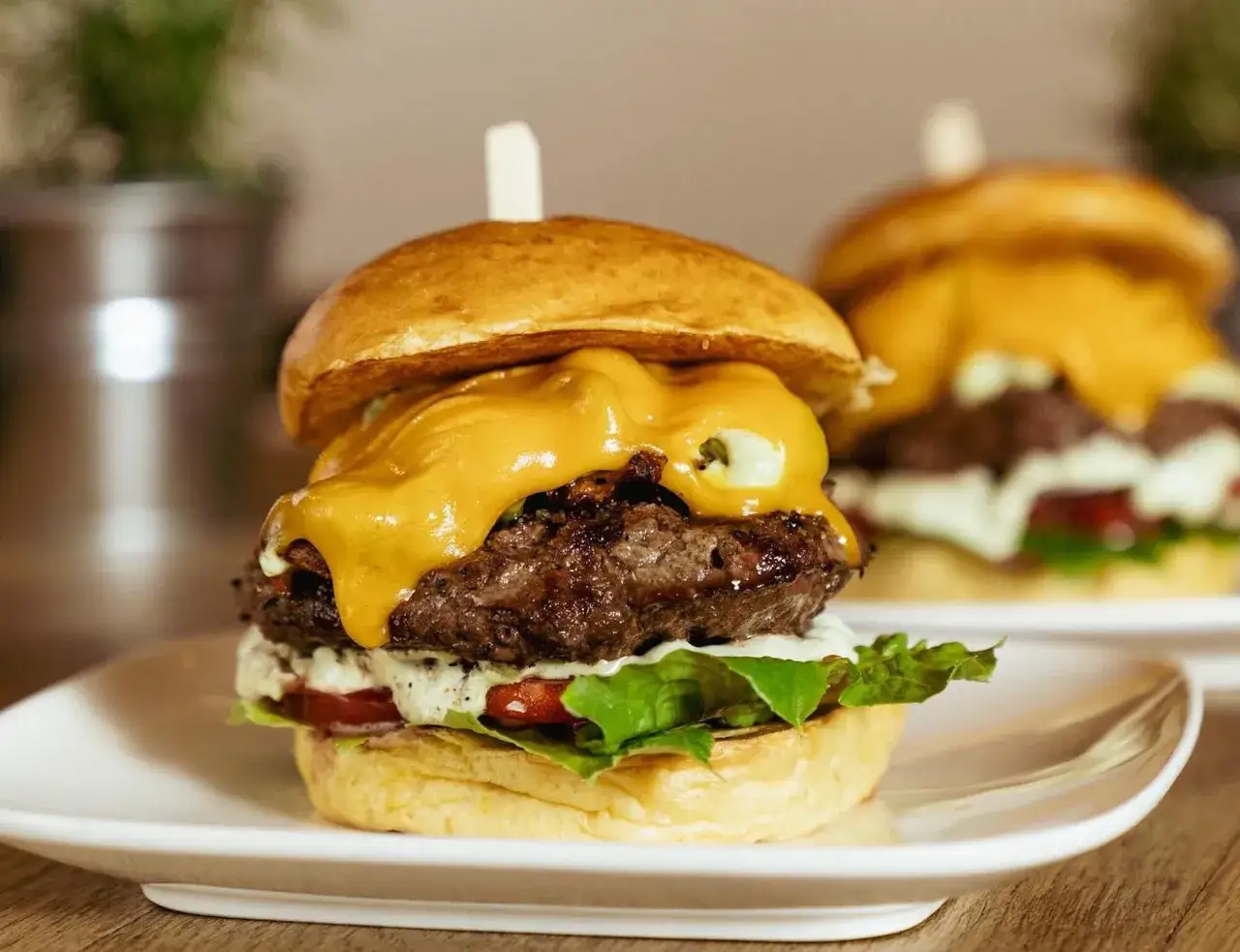 Saftiger Burger mit geschmolzenem Käse, Salat und Tomate. Der beste Burger in Köln, der auf einem Teller serviert wird.