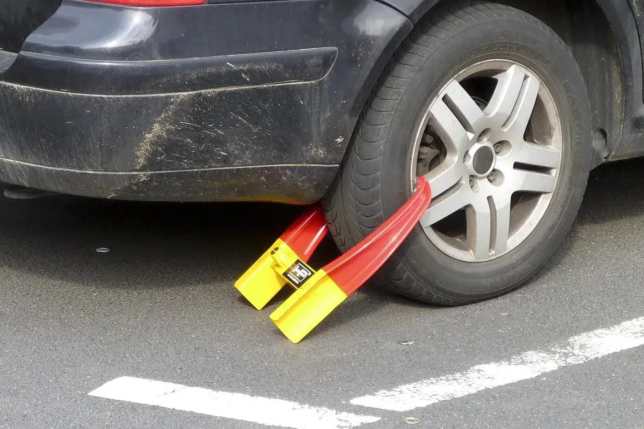 Ruota bloccata da ganasce rosse e gialle, segno di un fermo amministrativo auto.