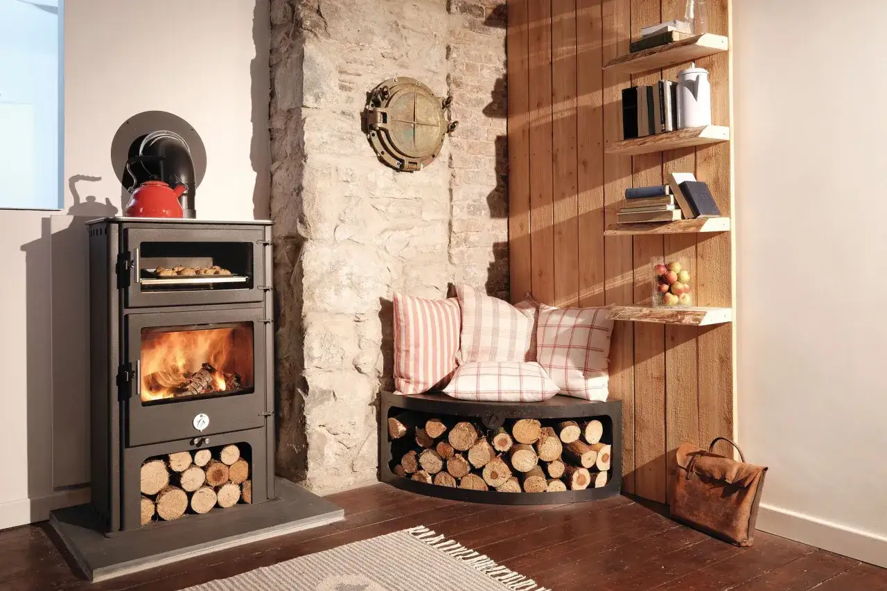 Gem&uuml;tliche Ecke mit Holzofen, Kaminholz und Kissen. Hier kann man den Holzbedarf berechnen und entspannen.