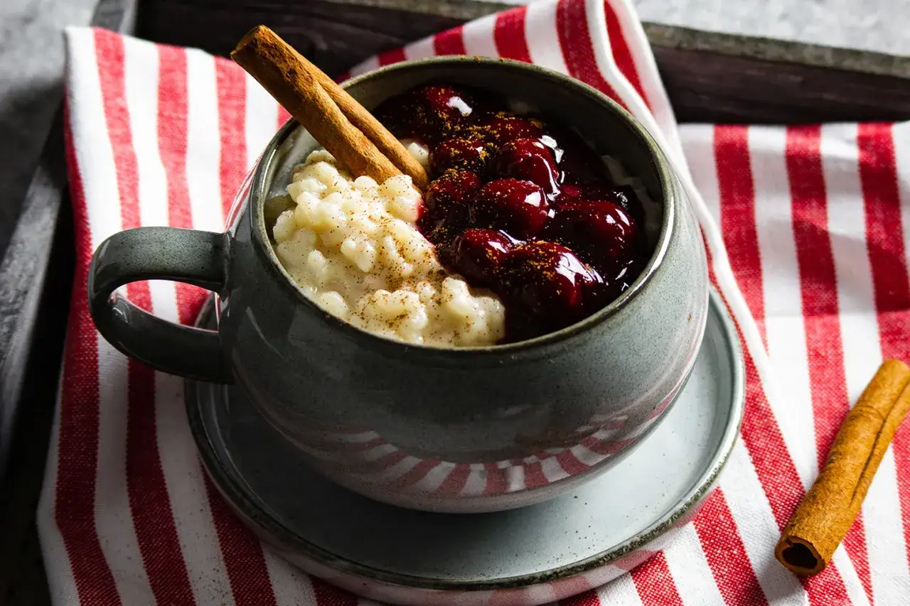 Cremiger Milchreis mit Kirschen und Zimt, ein köstliches Milchreis Rezept, garniert mit Zimtstangen.