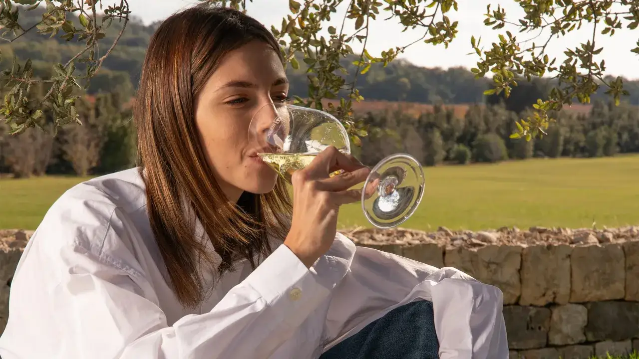 Donna assapora vino bianco in vigneto, un momento per capire se un vino è buono.