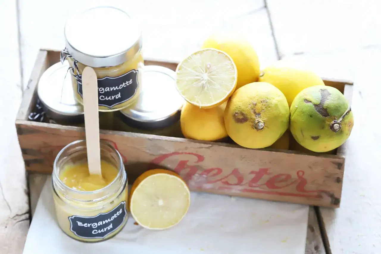 Frische Bergamotte Curd in Gläsern, daneben Zitrusfrüchte und eine Holzschale. Perfekt für ein bergamotte eis.