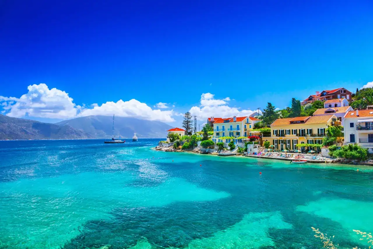 Widok na turkusowe morze i kolorowe domy na wzg&oacute;rzu. Kefalonia najpiękniejsze miejsca, idealne na wakacje.