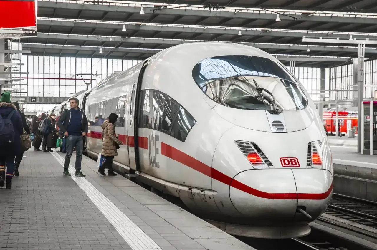 Ludzie czekają na peronie na pociąg ICE. Dowiedz się, jak kupić bilet na pociąg w Niemczech, korzystając z automat&oacute;w lub aplikacji.
